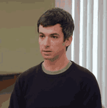 a man in a black sweater is looking at the camera .