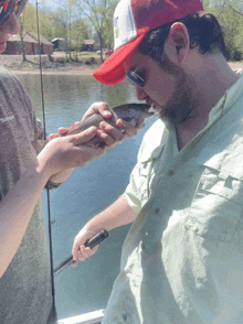 a man wearing a shimano shirt is holding a fish in his hands