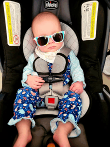 a baby wearing sunglasses is sitting in a car seat that says chicco