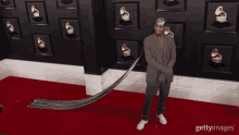 a man in a suit is standing on a red carpet in front of a wall with grammys on it