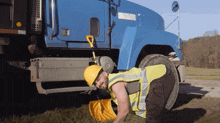 a man wearing a hard hat and safety vest is kneeling in front of a blue truck that says western star