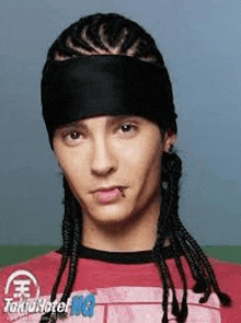 a young man with braids and a bandana on his head is wearing a red shirt .