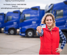 a woman in a red vest is holding a drivers license in front of a row of blue trucks