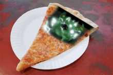 a slice of pizza on a paper plate with a green monster on it .