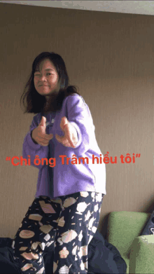 a woman in purple pajamas is giving a thumbs up with the words " chi ong tram hiu toi " in red