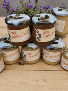 jars of miel toutes fleurs are stacked on a wooden table