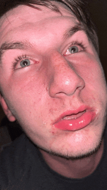 a close up of a man 's face with red lips and a black shirt