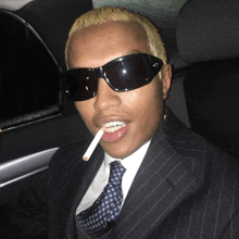 a man in a suit smoking a cigarette and wearing sunglasses