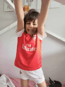 a little girl wearing a fly emirates shirt is hanging upside down