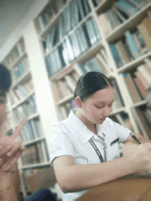 a woman in a white shirt with a lanyard that says ' ulysses ' on it sits at a desk