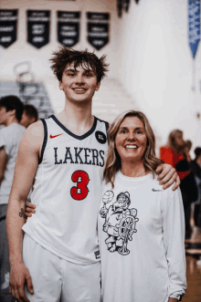 a boy wearing a lakers jersey poses with his mother