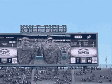 three soldiers are standing in front of a kyle field sign