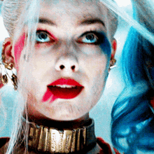 a close up of harley quinn 's face with red and blue paint on her face