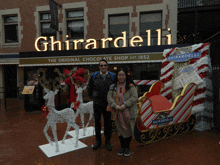 a man and woman pose in front of the ghirardelli store