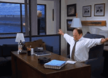 a man is stretching his arms while sitting at a desk in an office