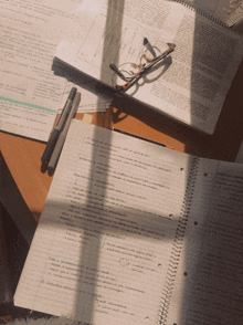 a stack of notebooks and a pair of glasses sit on a desk