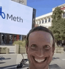 a man is smiling in front of a sign that says meth