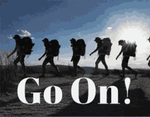 a group of people with backpacks are walking down a dirt road with the words go on in white letters