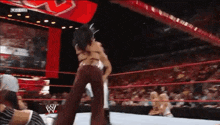 a woman is wrestling another woman in a wrestling ring while a crowd watches .