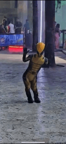 a young boy in a wolverine costume is standing on a sidewalk .