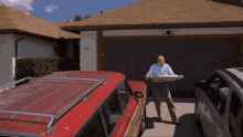 a man is carrying a tray of food in front of a house with the number 746 on the garage door