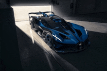 a blue and black sports car is parked in a dark garage