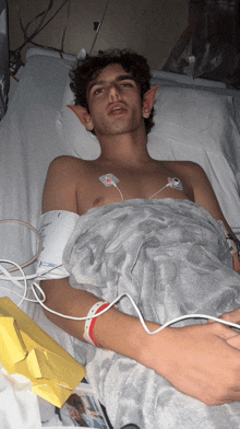 a young man is laying in a hospital bed with a blanket