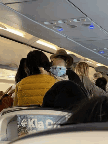 a woman holding a baby wearing a face mask on an airplane with a kia c magazine