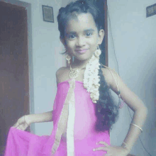 a little girl is wearing a pink dress and a gold necklace