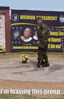 a man in a military uniform is standing next to a bouquet of flowers in front of a mkmva president sign .