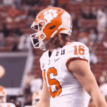 a football player wearing a helmet and a white jersey with the number 16 on it is standing on the field .