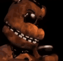 freddy fazbear from five nights at freddy 's is holding a microphone in his hand in a dark room .