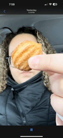 a woman is holding a donut in her hand and the time is 6:58