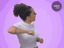 a woman in a white shirt is dancing in front of a purple background that says salon line