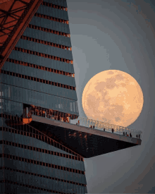 a full moon is visible in the sky above a building