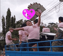 a man in a pink shirt is holding a pink heart in his hand