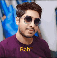 a man wearing sunglasses and a purple shirt that says bah