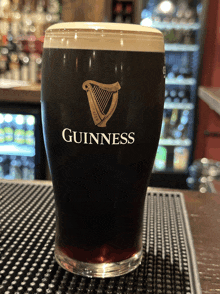 a full glass of guinness sits on a bar top