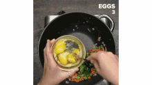 a person is adding eggs to a pan of vegetables