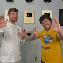 two men waving their hands in front of a wall with a youtube play button