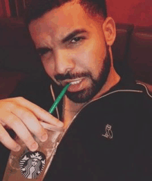 a man with a beard is drinking from a starbucks cup with a straw .