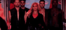 a group of men and a woman are standing next to each other in a dark room .