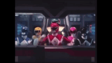 a group of power rangers are standing next to each other in a dark room .