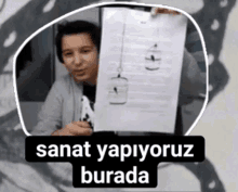 a man holding a piece of paper with the words sanat yapiyoruz burada written on it