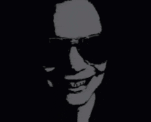 a silhouette of a man wearing sunglasses and smiling in the dark .