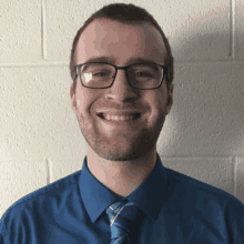 a smiling man wearing glasses and a blue shirt