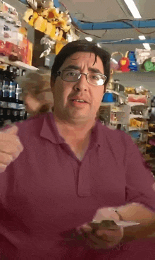 a man wearing glasses and a pink shirt is standing in front of a shelf full of stuffed animals