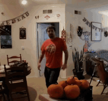 a man in a red shirt stands in a living room with a banner that says " day of the dead "