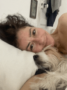 a woman is laying on a bed with a small dog