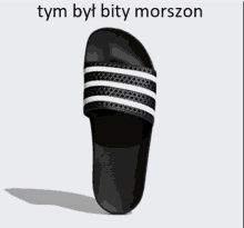 a pair of black and white adidas slides with the words tym byl bity morzon above them